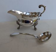 A George V silver sauce boat with wavy rim border, scroll handle and shell capped pad feet