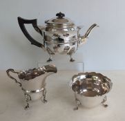 An Edwardian silver teapot with wavy rim wood handle, raised on four feet, hallmarked for Martin Hal