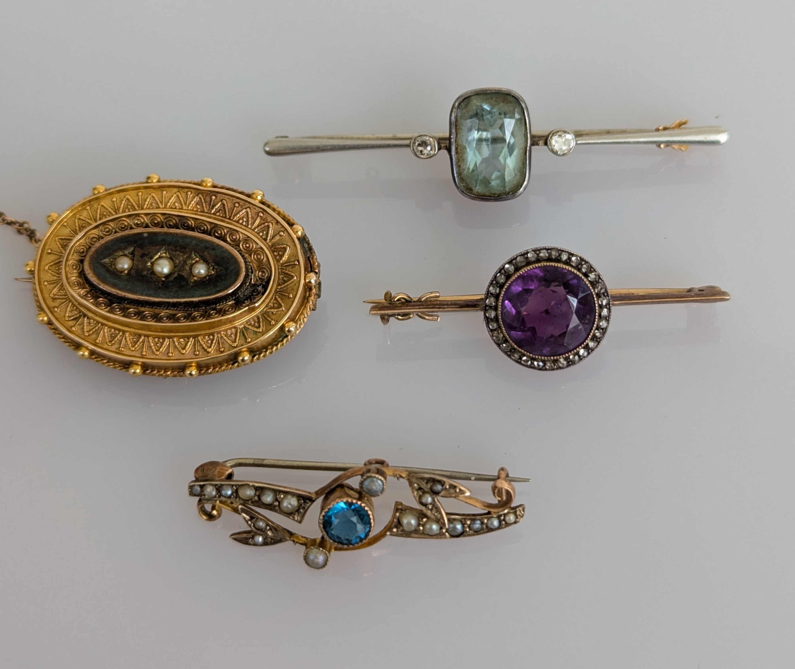 An assortment of four Victorian and Edwardian gem-set and seed pearl brooches, all stones and clasps