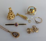 A yellow gold pierced gem-set fob, 33mm; a faceted crystal pendant in a gold frame; a ribbon bell