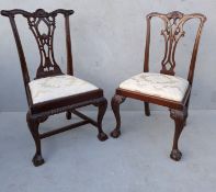 Two Chippendale-style mahogany dining chairs with carved splats, fabric upholstered seats