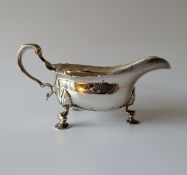 A late Victorian silver sauce boat with wavy rim, scroll handle on three hoof feet, 18.5 cm W