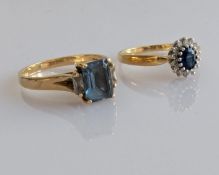 A baguette-cut blue topaz ring in a yellow gold claw setting and an oval sapphire cluster ring