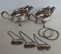 A pair of Georgian-style silver sauce boats with carved rims, scroll handles and hoof feet