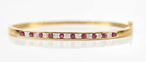 A 9ct yellow gold synthetic ruby and diamond set hinged snap bangle, internal measurement 16cm,