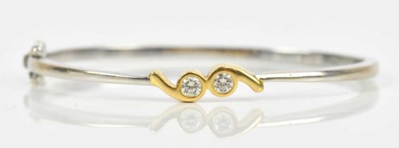 A yellow and white metal diamond set hinged snap bangle, stamped '750', set with two brilliant cut
