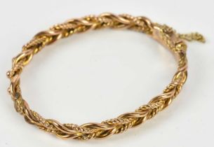 A yellow metal hinged snap bangle, stamped '9ct', approx 11.84g.