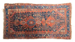 A Kurdish rug, the indigo field with a row of geometric shaped and hooked pointed medallions,