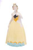 An Austrian Wiener Werkstatte pottery figure of a girl wearing a yellow shirt and holding a black