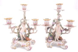 A pair of Berlin [KPM] porcelain three-branch candelabra in the form of putti standing by entwined