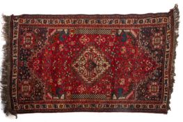 A Shiraz carpet, of small size, the madder field with a central ivory stepped medallion,
