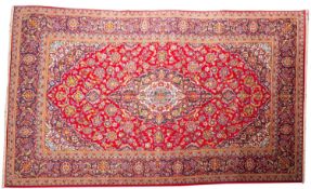 A Kashan carpet, the madder cartouche field with a central indigo,