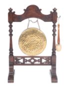 A late Victorian oak and brass hung gong, late 19th century; hung within an arch topped frame,