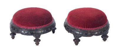 A pair of Victorian carved and ebonised circular footstools,