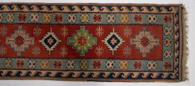 A Turkish runner, the brick red field with a row of serrated and stepped medallions,
