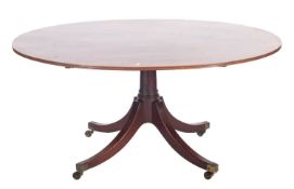 A mahogany oval breakfast table in Regency style; the single piece flip top with reeded edges;