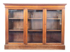 An Edwardian oak low bookcase, enclosed by three glazed panel doors and with adjustable shelves,