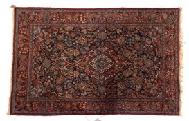 A Kashan rug, the indigo cartouche field with a central red,