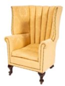 An upholstered wing back armchair in Queen Anne style,