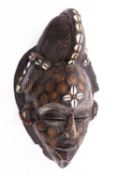 A carved wood, cowrie shell and coin inset mask, probably Tikar Tribe, Cameroon,