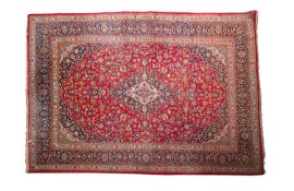A Kashan carpet, the rose cartouche field with a central indigo and ivory lozenge pole medallion,