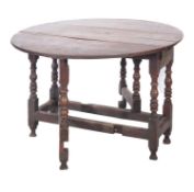 An oak gateleg oval table, early 18th century; with twin drop leaves and a drawer at each end,
