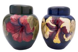 Two Walter Moorcroft pottery jars and covers tube lined in the Hibiscus pattern reserved on a blue
