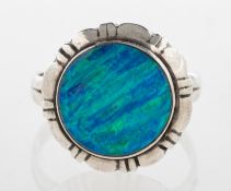 A black opal ring, collet set with a circular plaque of black opal in a carved mount, marked 925,