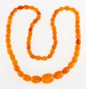 A strand of graduated amber beads, an unstrung strand of graduated oval amber beads, length approx.