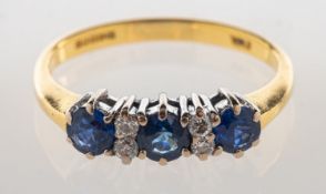 An 18ct gold sapphire and diamond ring, claw set with three circular-cut sapphires,