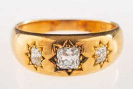 An antique three stone diamond ring, star set to the centre with an old mine-cut diamond,