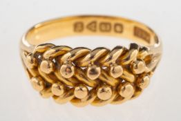 An early 20th century 18ct gold 'keeper' ring, with plait section to front and 'V' split shoulders,
