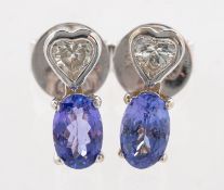 A pair of tanzanite and diamond stud earrings, each bezel set with a heart-shaped diamond,