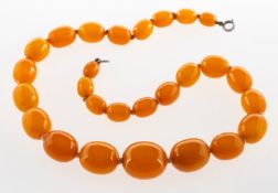 A butterscotch 'amber' type bead necklace, graduated oval butterscotch 'amber' type beads, knotted,