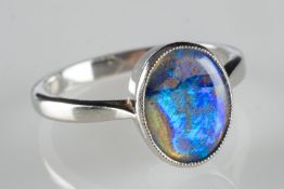 A modern black opal ring, collet set wit