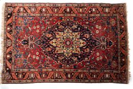 A Tabriz carpet, the brick red field with an indigo and ivory flowerhead and lozenge pole medallion,