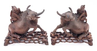 A pair of Chinese root wood carvings of a boy on a buffalo with inset bone eyes and teeth,