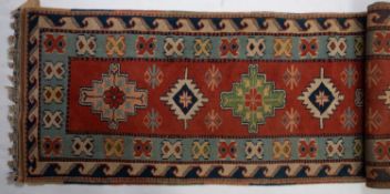 A Turkish runner, the brick red field with a row of serrated and stepped medallions,