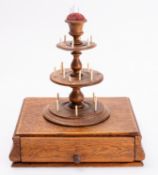 A Regency oak sewing stand, early 19th century; the Campana urn finial with pin cushion,