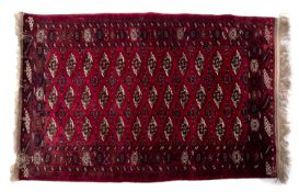 An Iranian Turkoman 'silky' rug, the madder field with three rows of quartered lozenge,