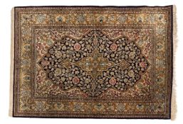 A Qum silk rug, the shaded indigo cartouche field with a central pistachio pole medallion,