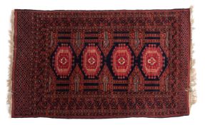 A Turkoman rug, the field with four hexagonal indigo and red hooked medallions,