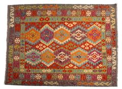 A Turkish Kelim, the hexagonal and lozenge field in bright colours of puce, rust,