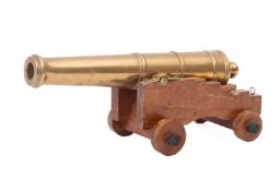 A 20th Century brass desk cannon. Mounted on a wooden carriage with wheels, 10cm high, 27cm long.