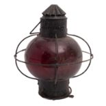 A wrought iron ship's lantern of circular form with red glass shade, 39cm high, 34cm diameter.