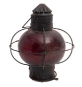 A wrought iron ship's lantern of circular form with red glass shade, 39cm high, 34cm diameter.