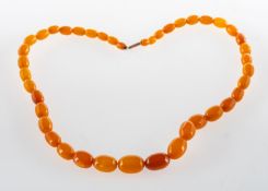 A string of 'amber type' beads, graduated oval beads to a barrel clasp, clasp marked 9ct,