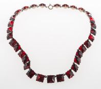 An antique costume jewellery necklace, claw and enclosed back set with square-cut red paste stones,