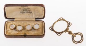 A pair of gilt cufflink's and an ornately mounted magnifying glass,