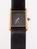 les must de Cartier a lady's gold-plated wristwatch the black rectangular dial having gilt Dauphine